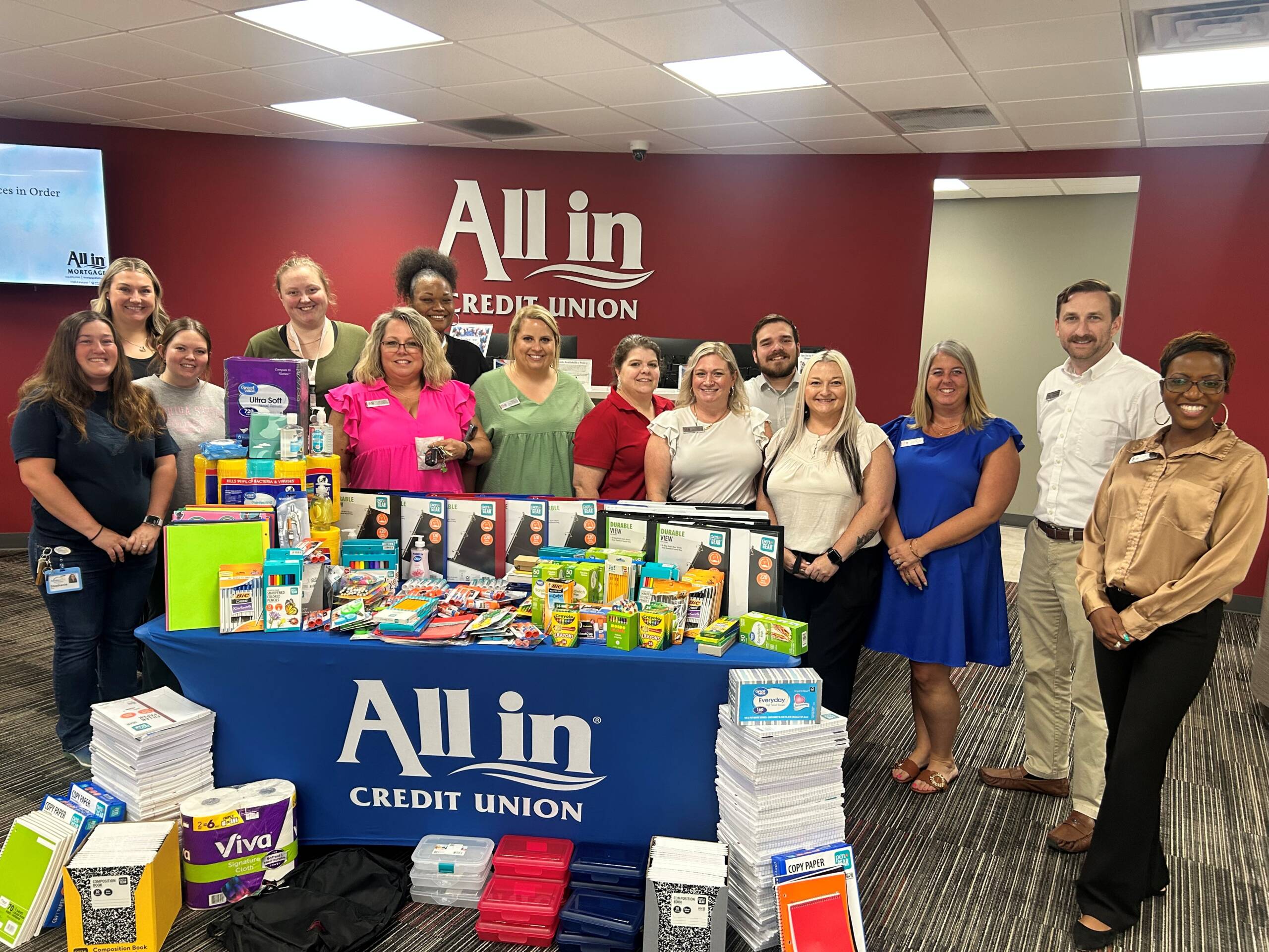 All in Credit Union and FamiliesFirst Network team members pose with donated school supplies.