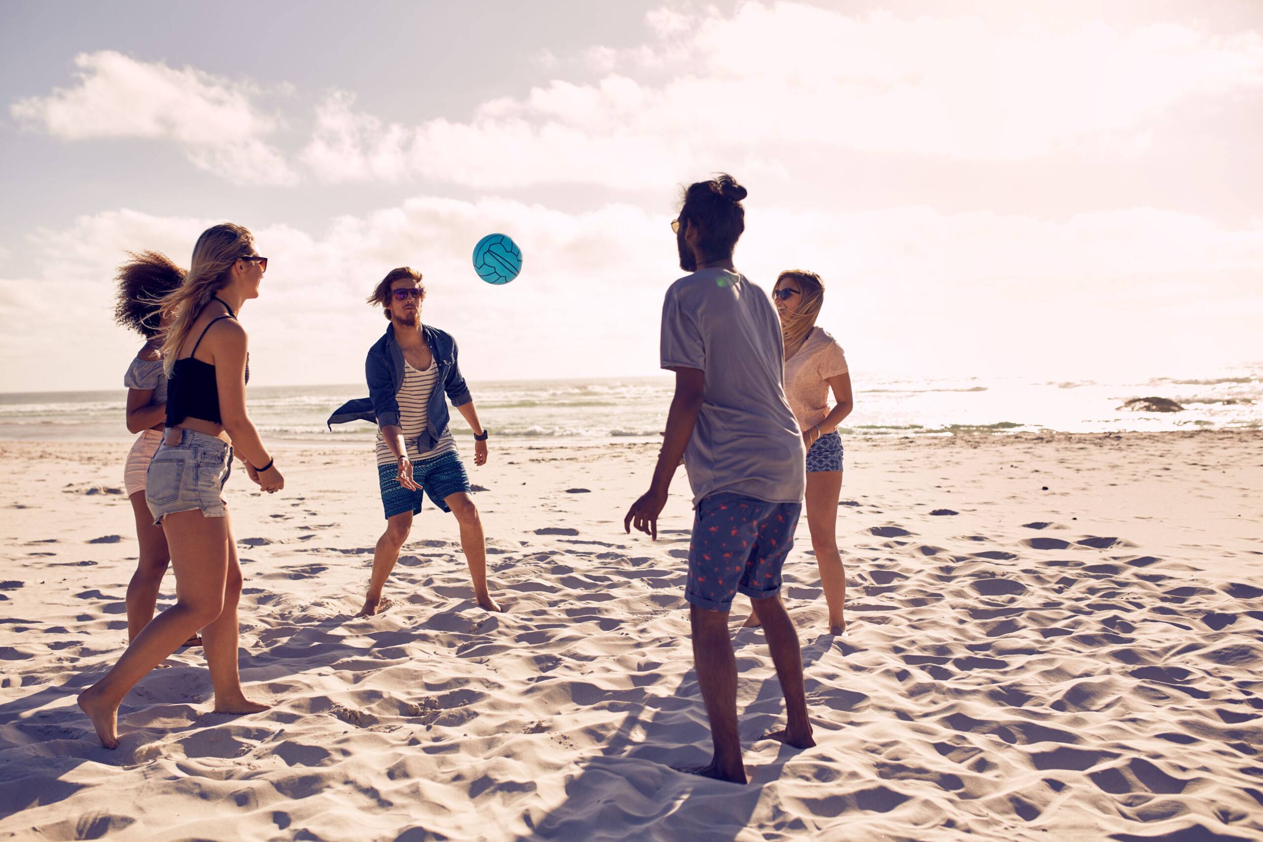 young adults playing volleyball on the beach